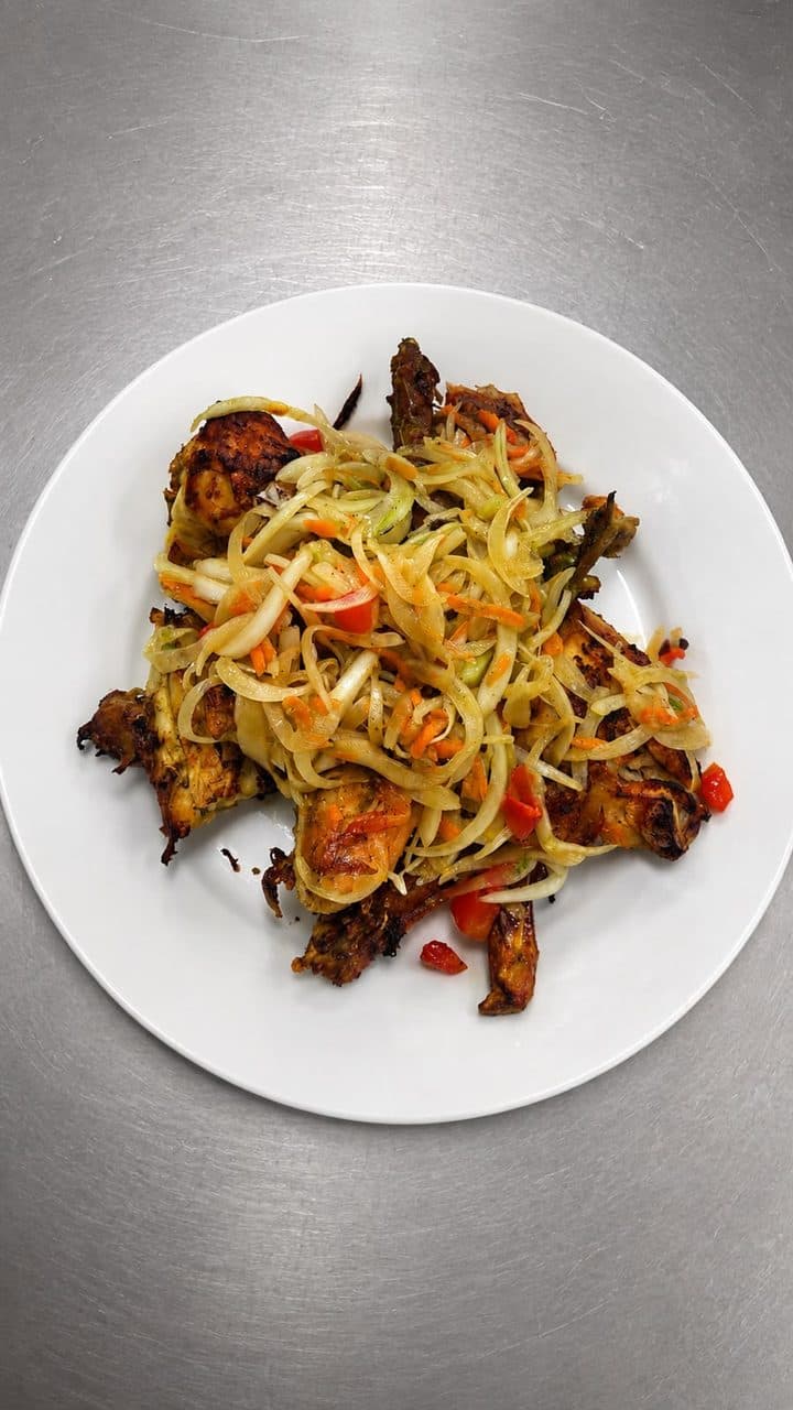 Émincé de viande grillée aux oignons et piments, servi dans une assiette blanche